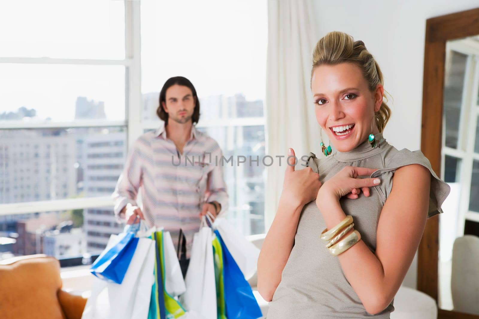 Young woman laughing with a young man holding shopping bags behind her