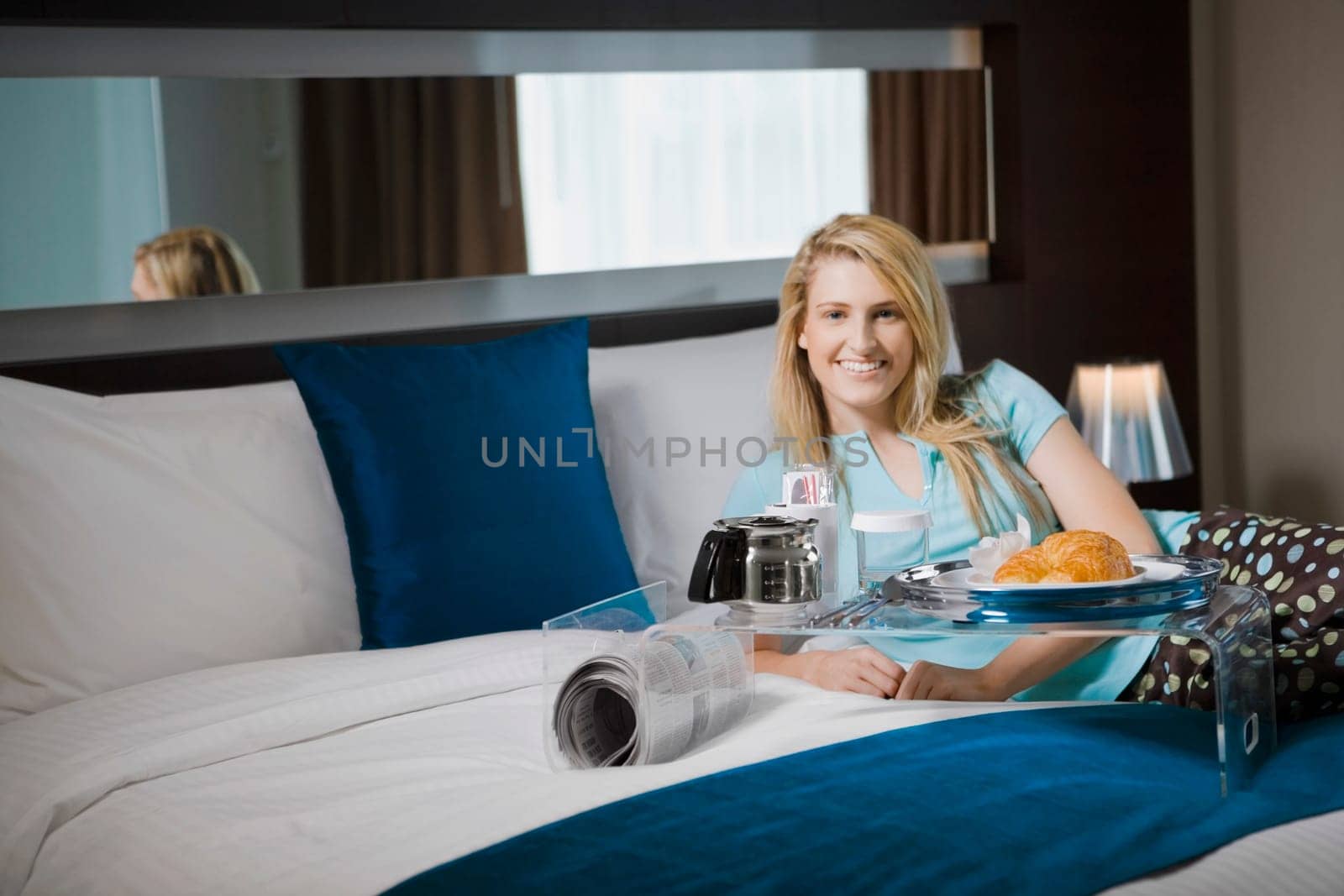 Portrait of a young woman having breakfast on the bed