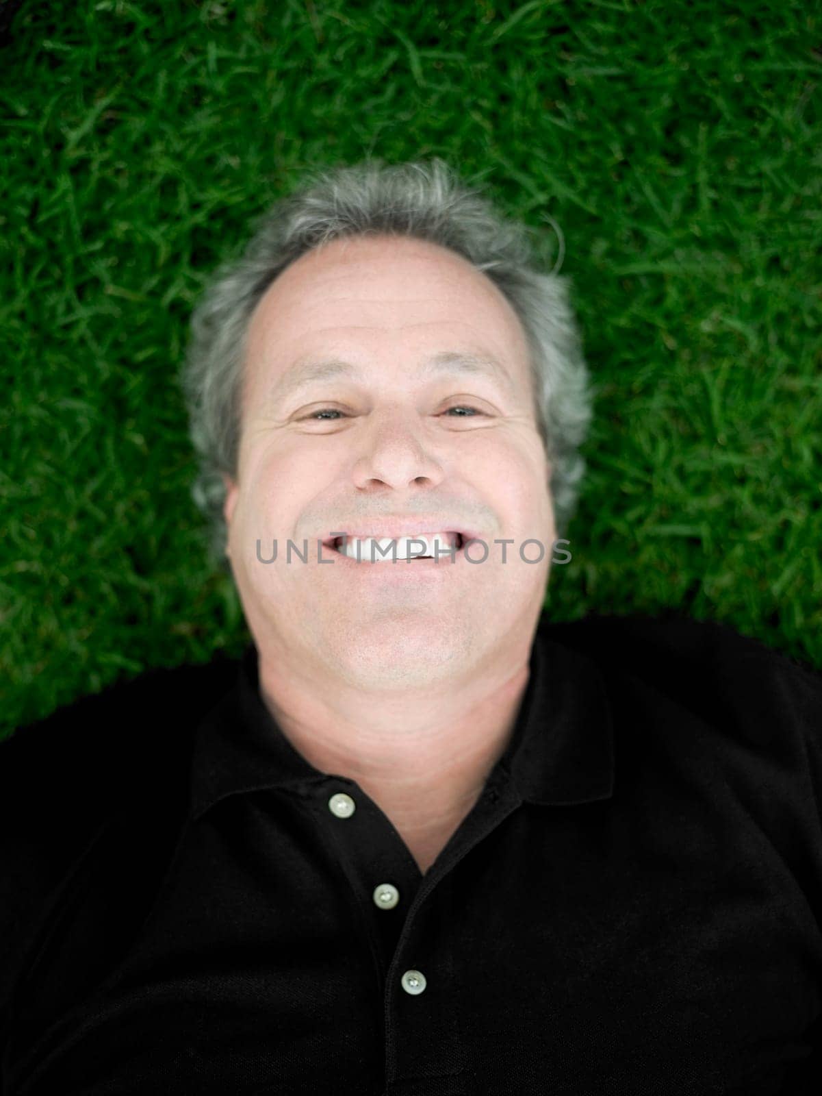 Portrait of a mature man lying on the grass and smiling