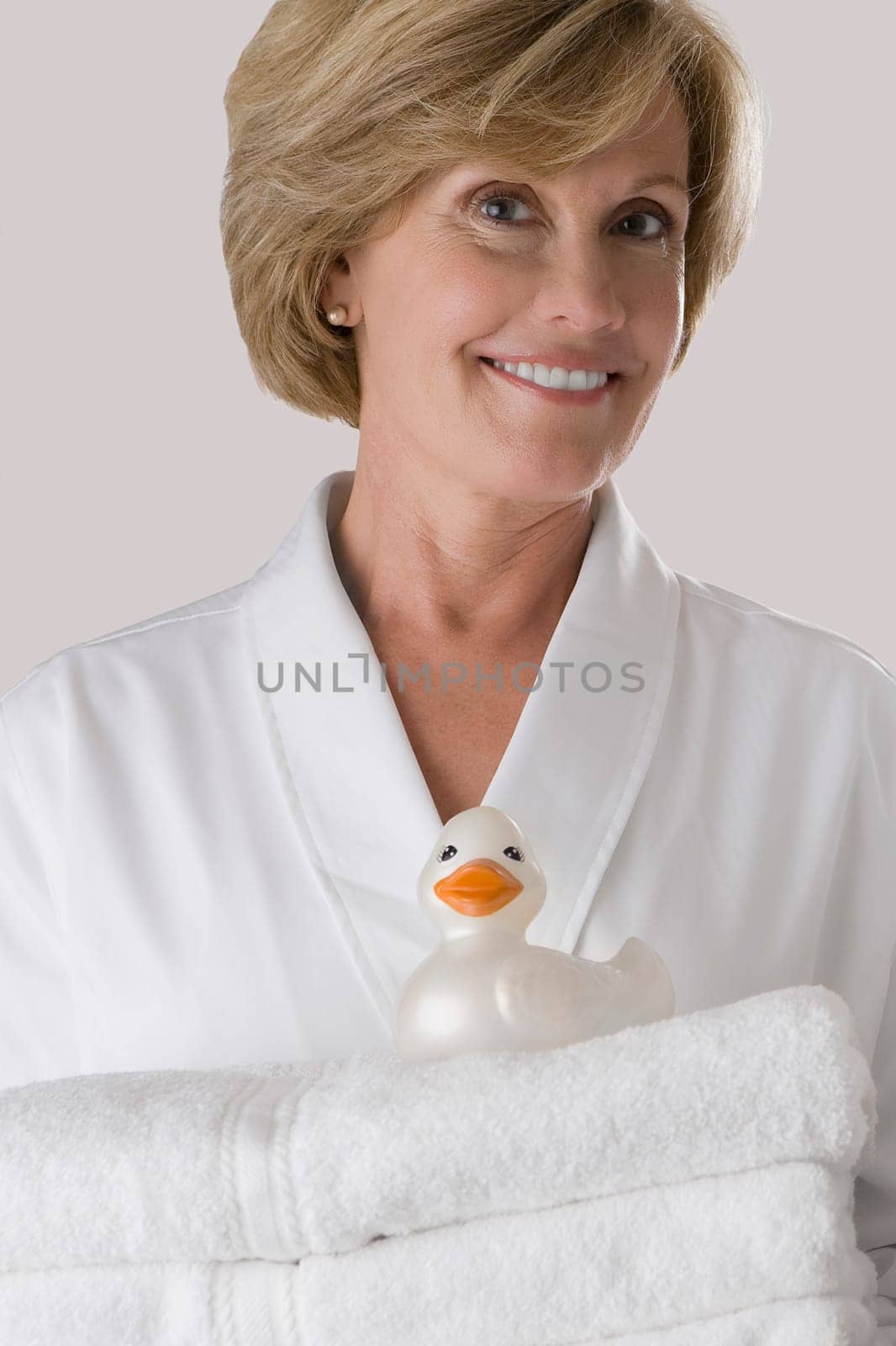 Portrait of a mature woman holding a stack of folded towels