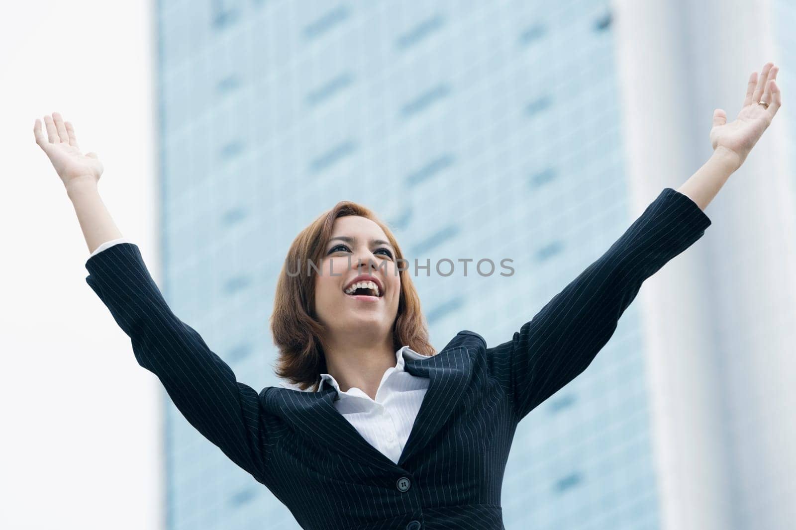 Close_up of a businesswoman smiling with her arms raised