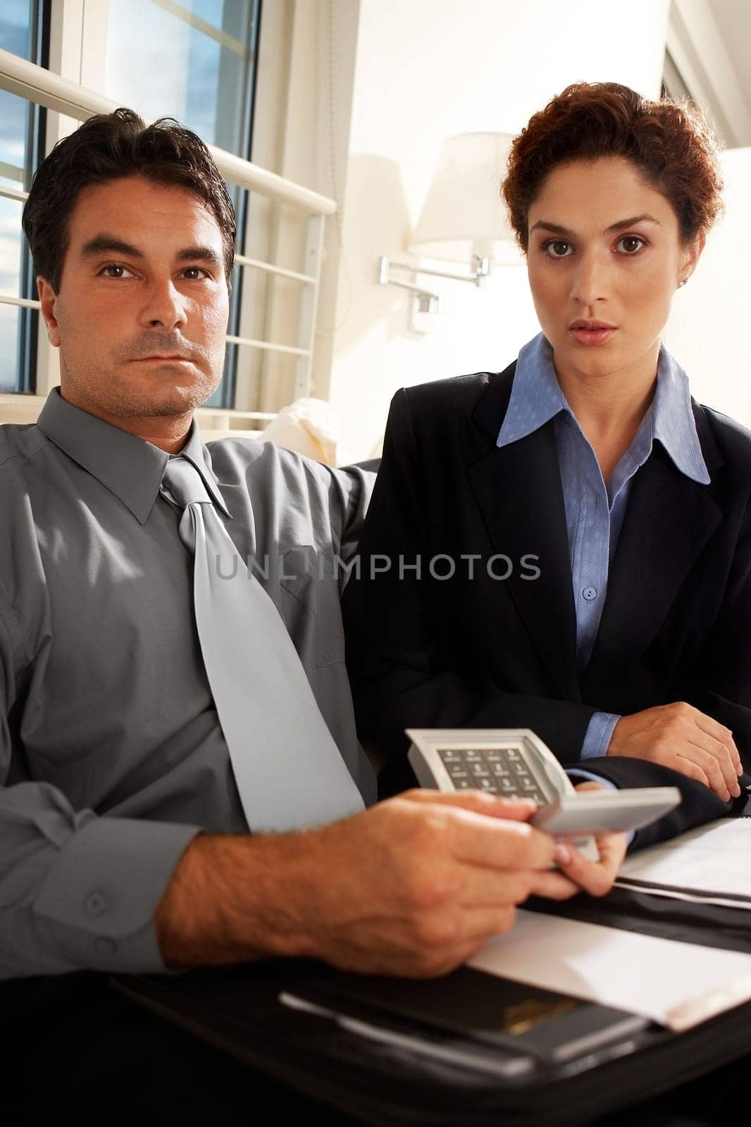 Portrait of a businessman sitting with a businesswoman holding a calculator