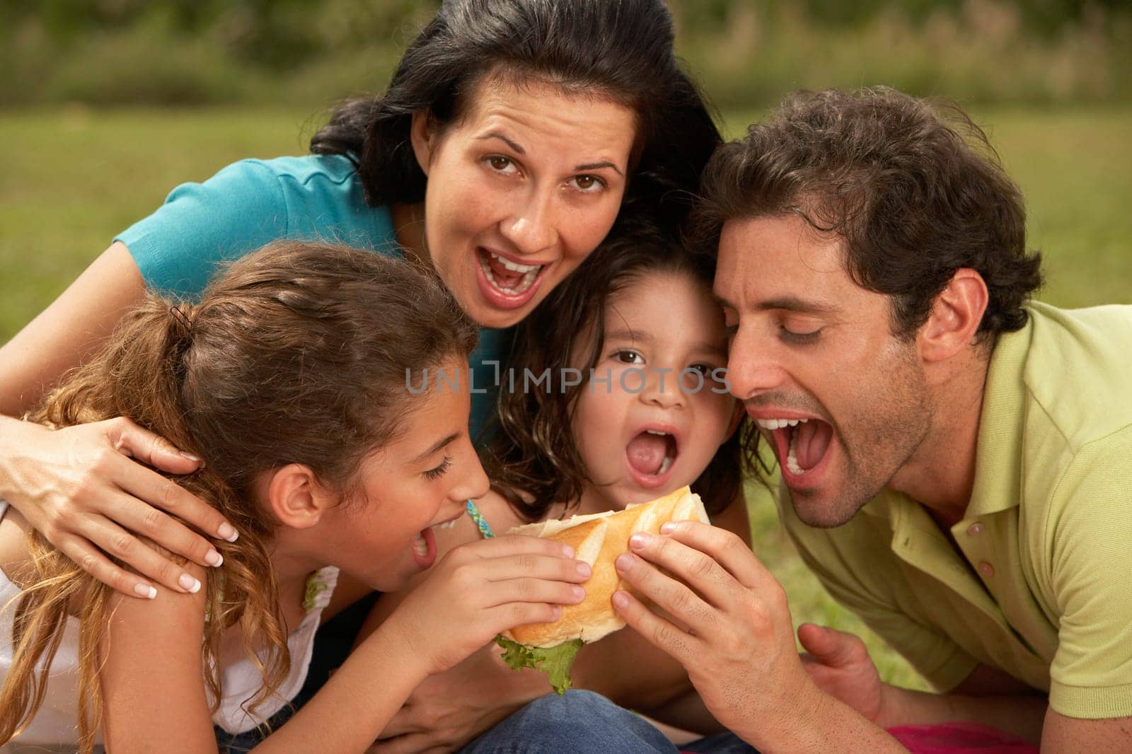 Mid adult man and a young woman eating a burger with their two daughters