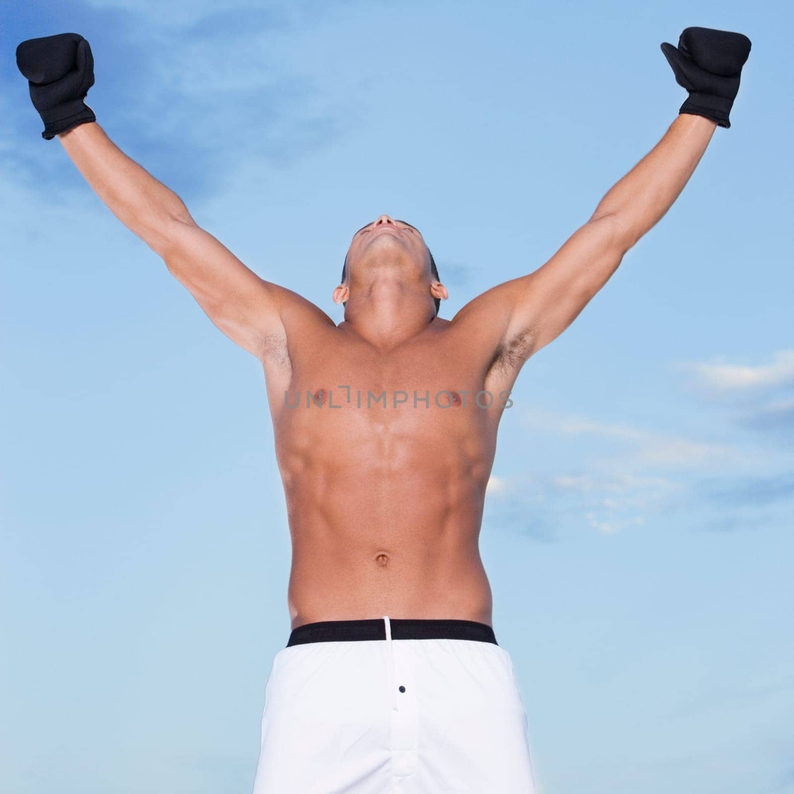 Low angle view of a young man with his arms raised