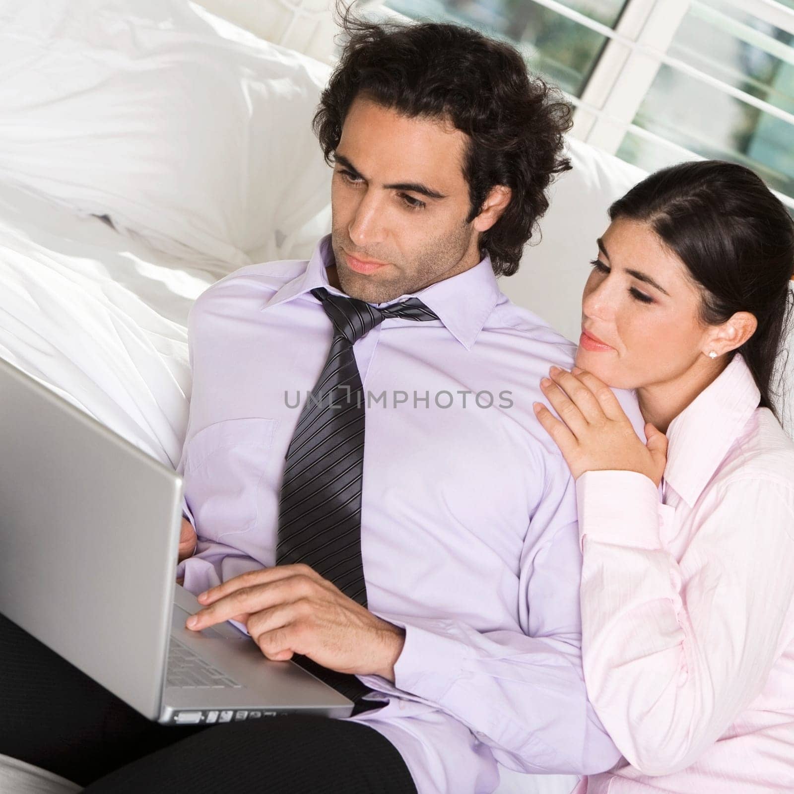 Close-up of a businessman and a businesswoman sitting on the bed using a laptop