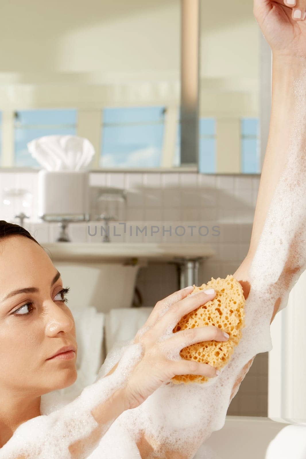Close-up of a young woman using a bath sponge on her arm