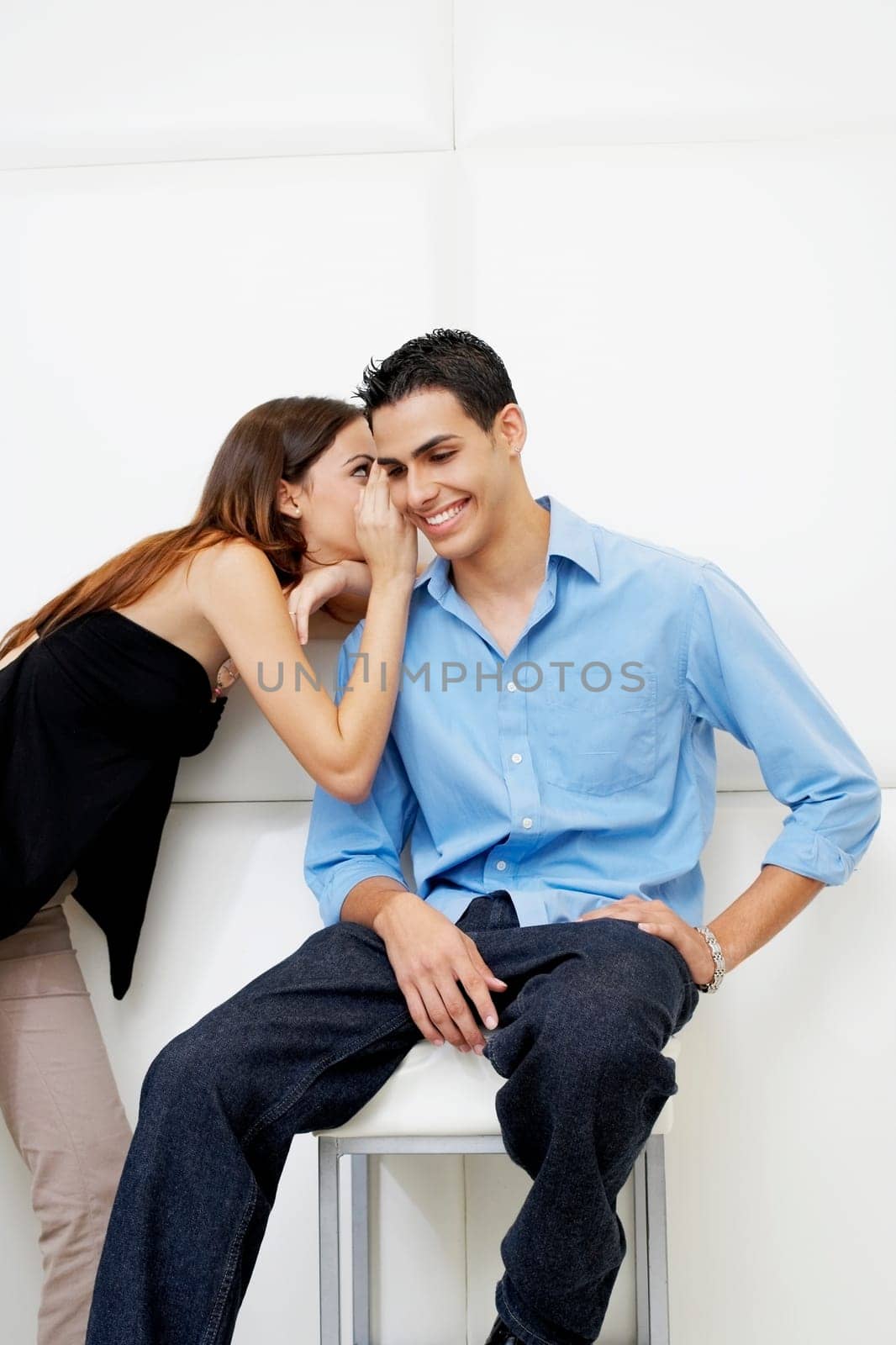 Side profile of a young woman whispering to a young man