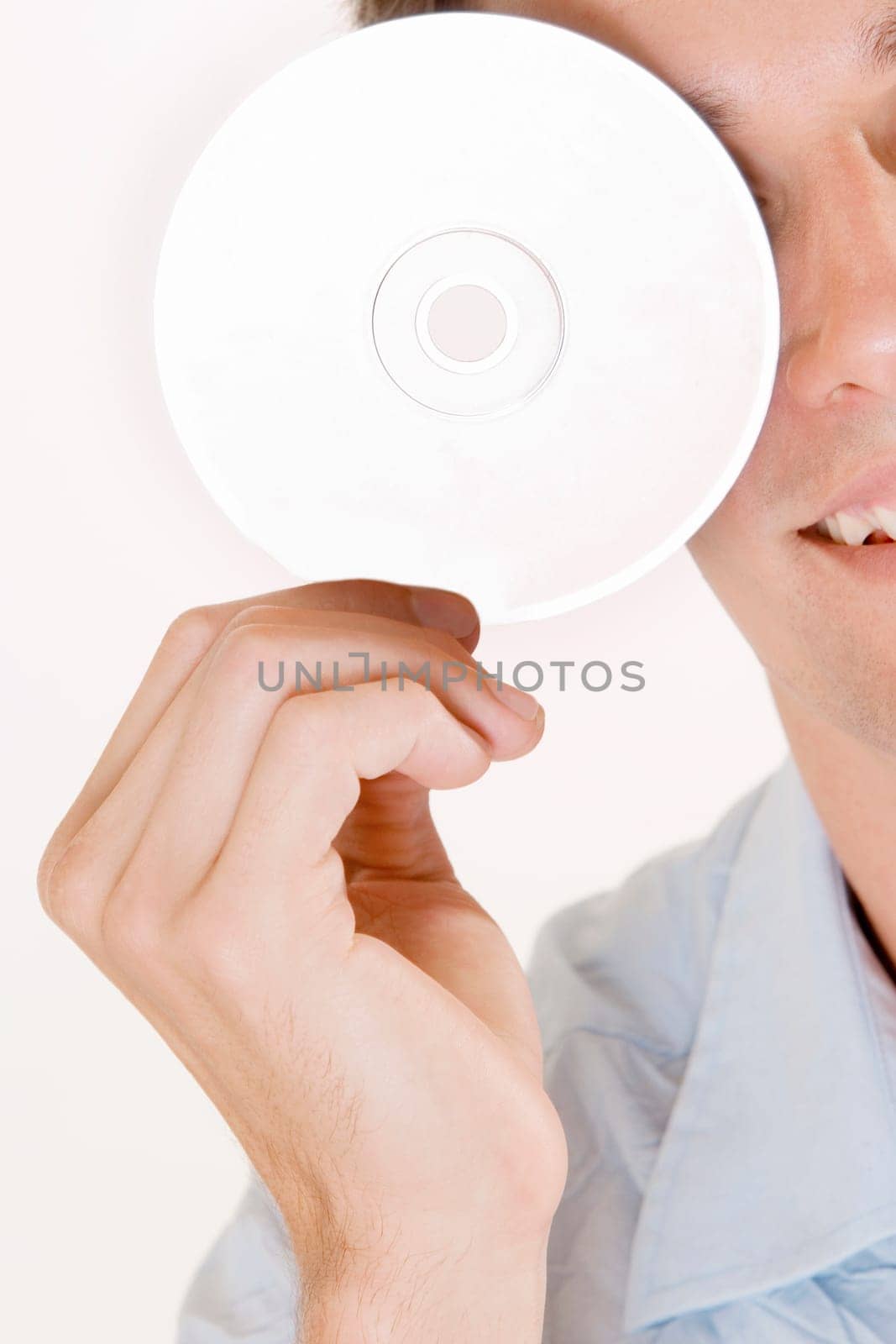 Close-up of a young man holding a CD in front of his eye