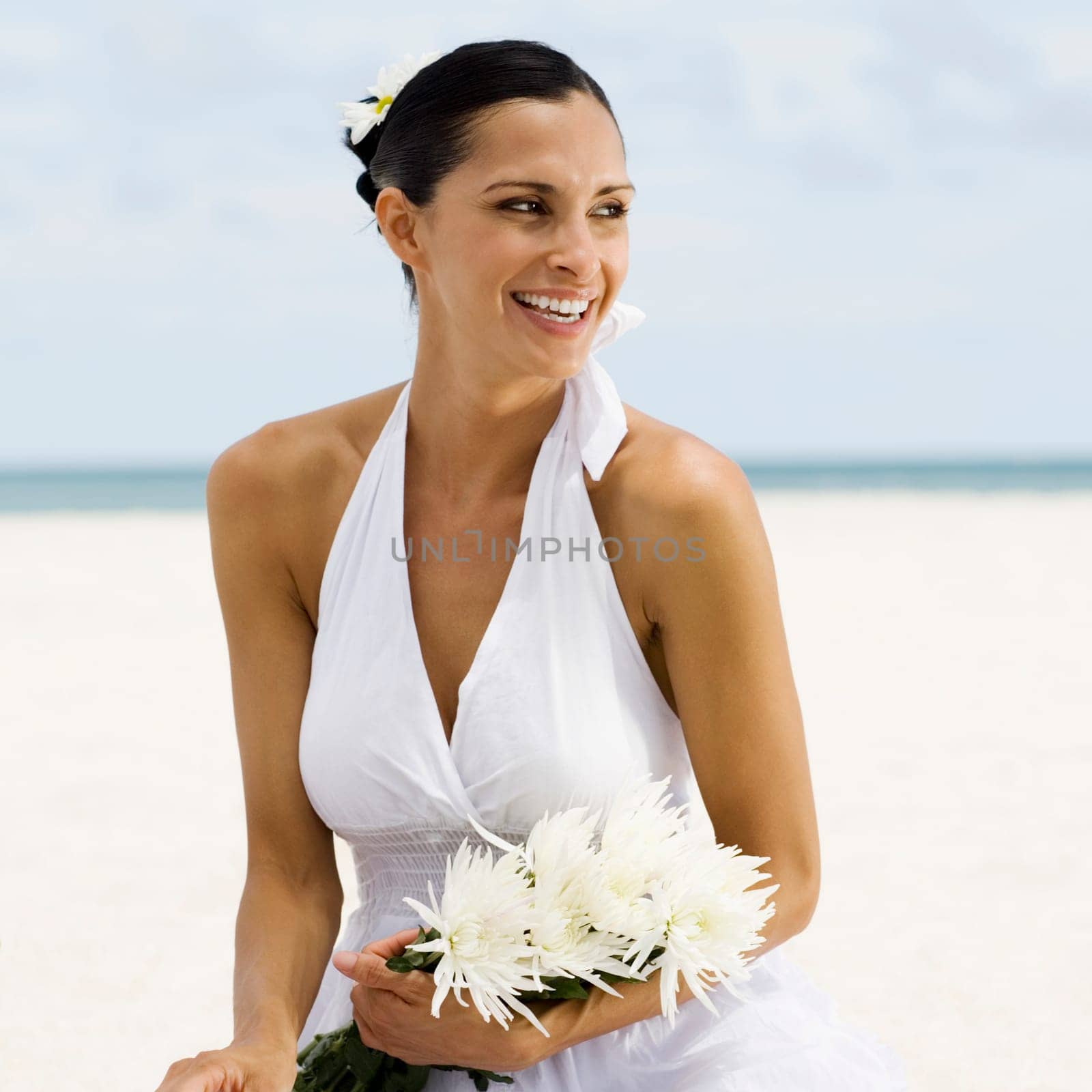 Close-up of a young woman smiling and sitting on the beach