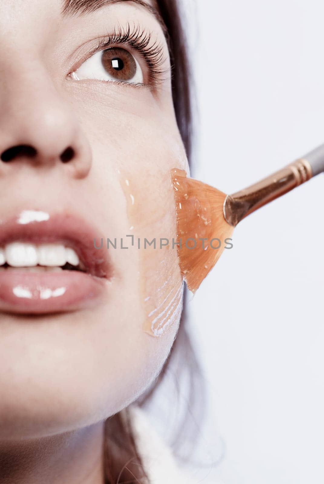 Close-up of a young woman applying a facial mask