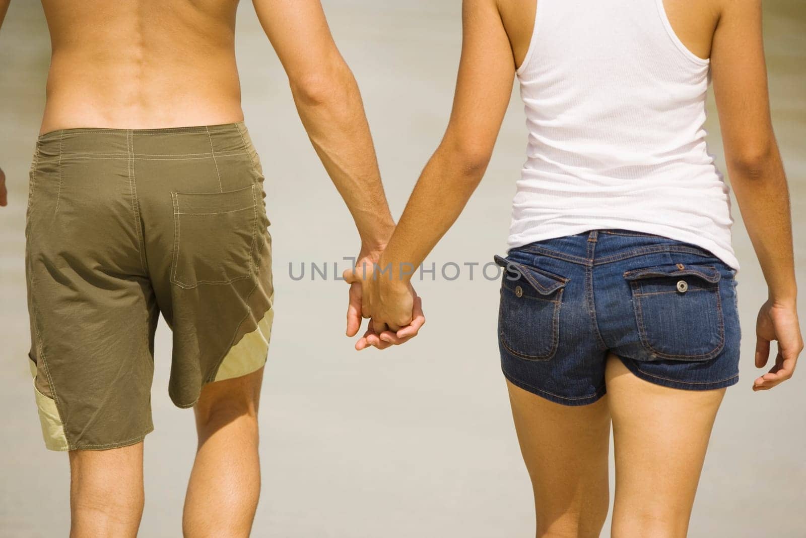 Mid section view of a young man and a teenage girl holding hands