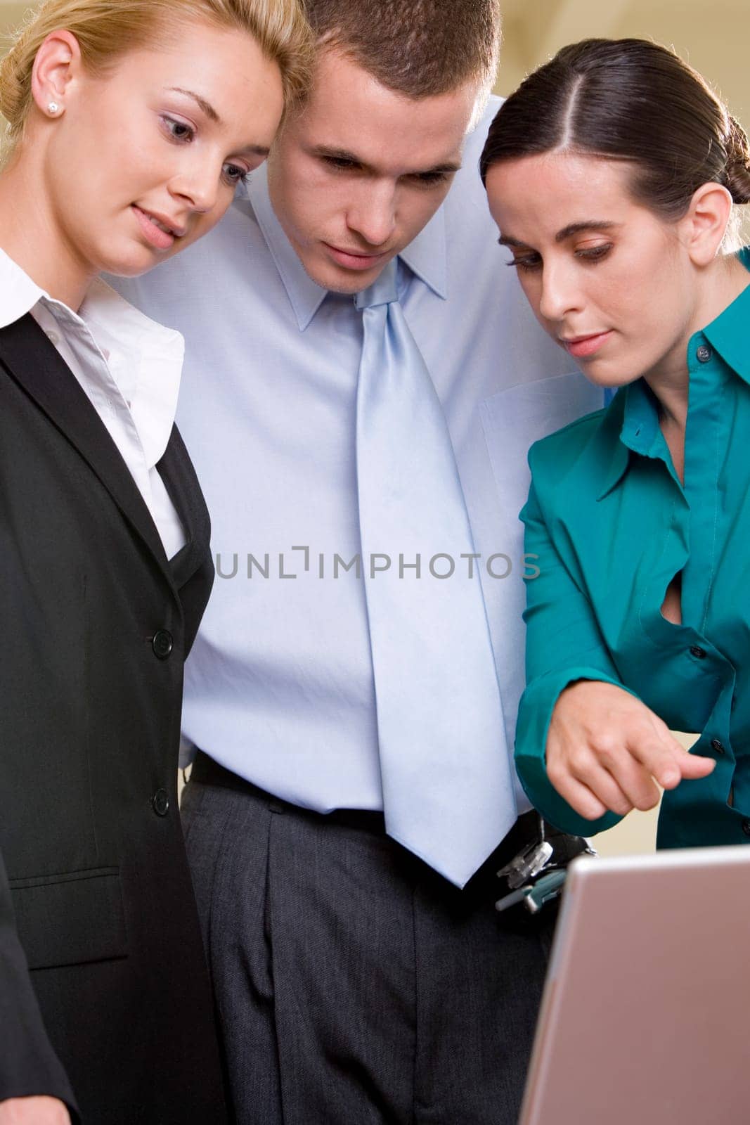 Close-up of two businesswomen and a businessman looking at a laptop