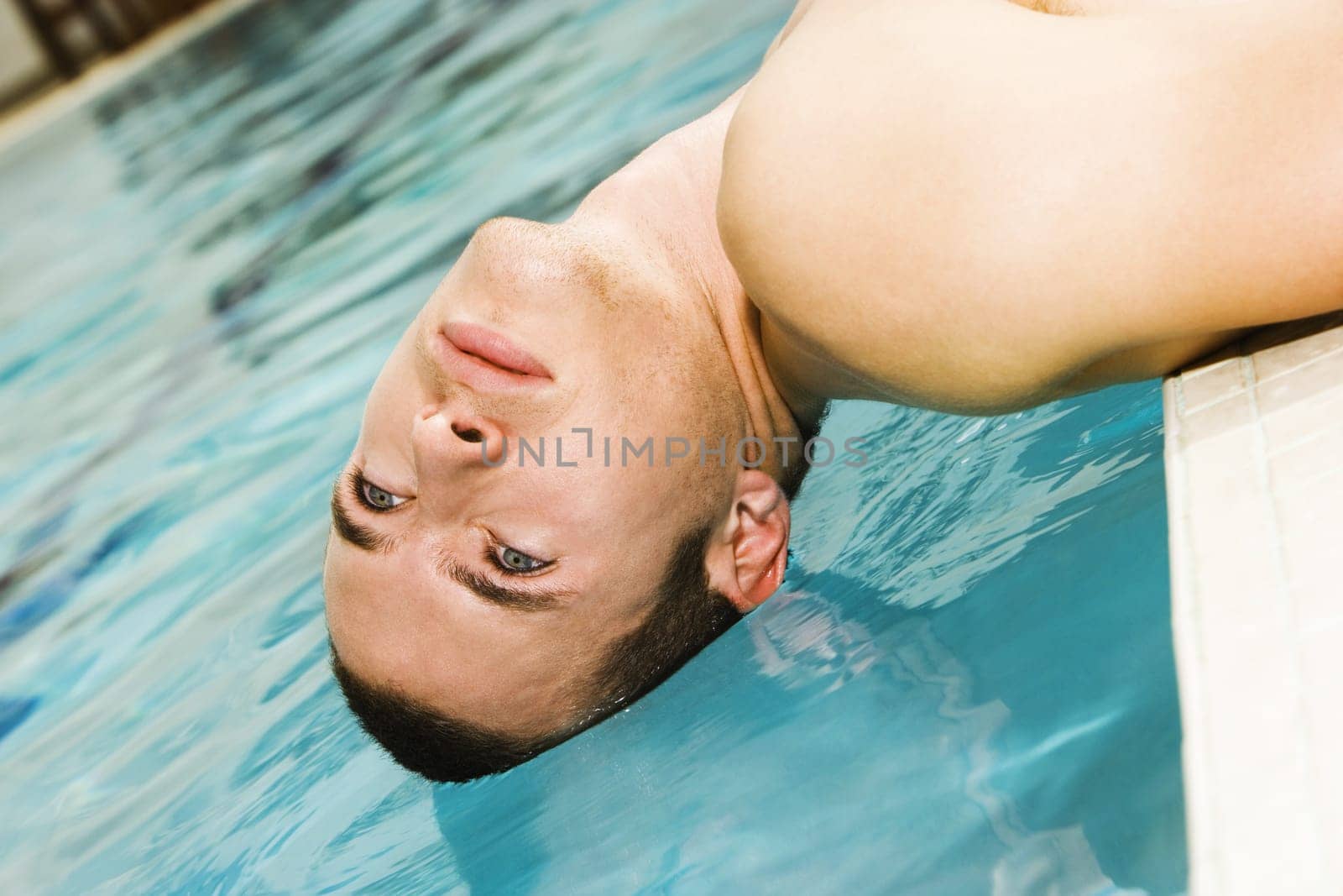 Close-up of a young man lying at the poolside