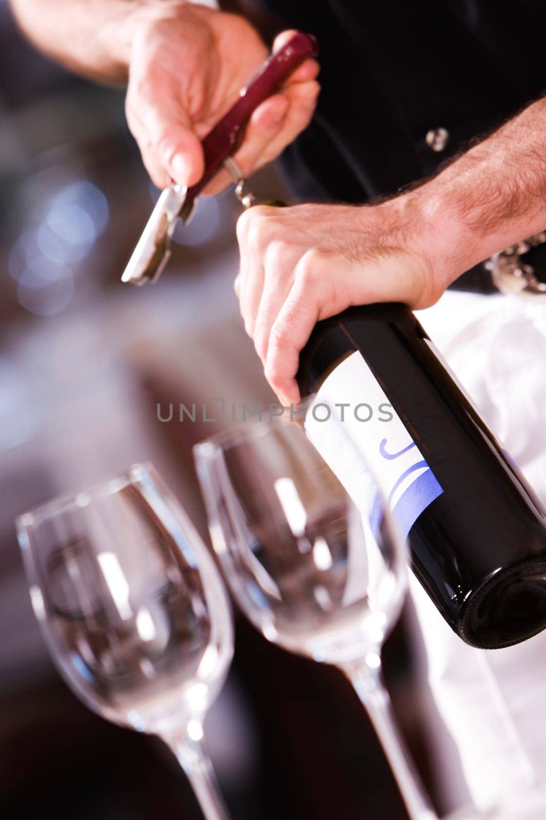 Mid section view of a man opening the cork of a wine bottle