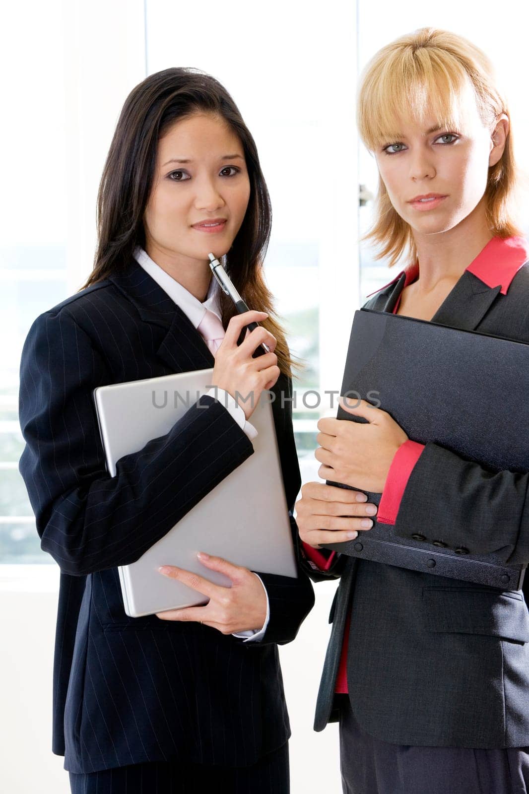 Portrait of two businesswomen holding a file and a laptop