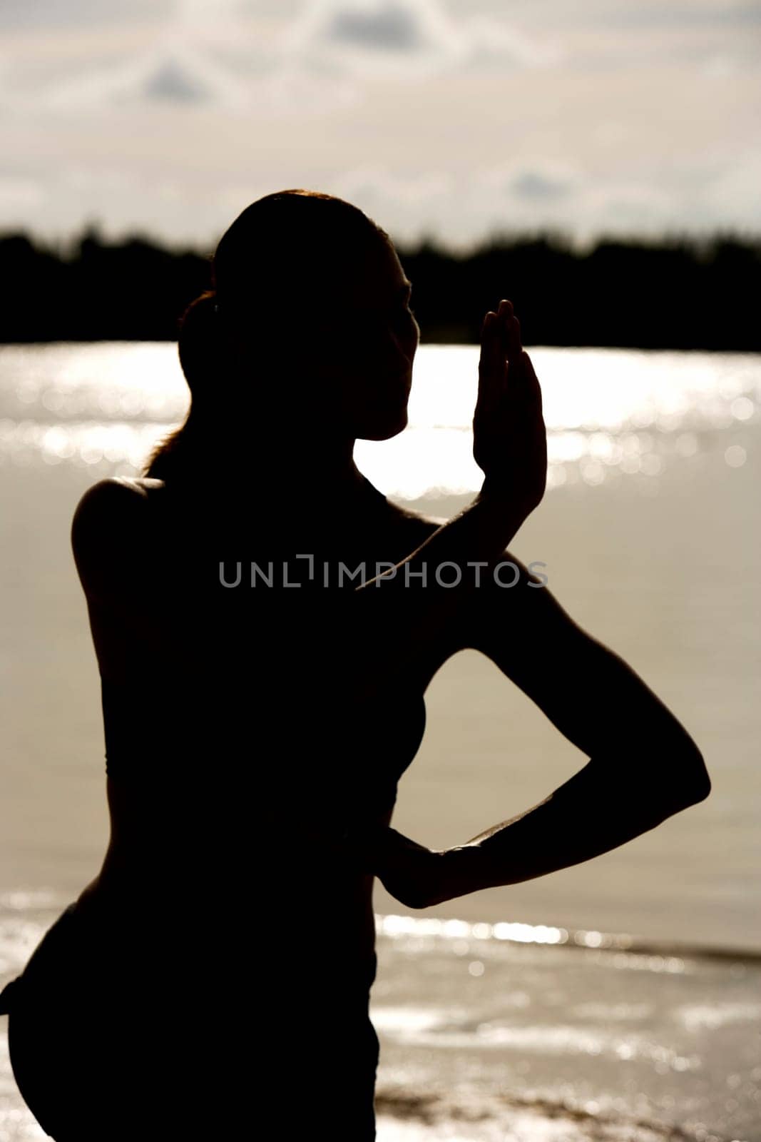 Silhouette of a young woman practicing martial arts on the beach