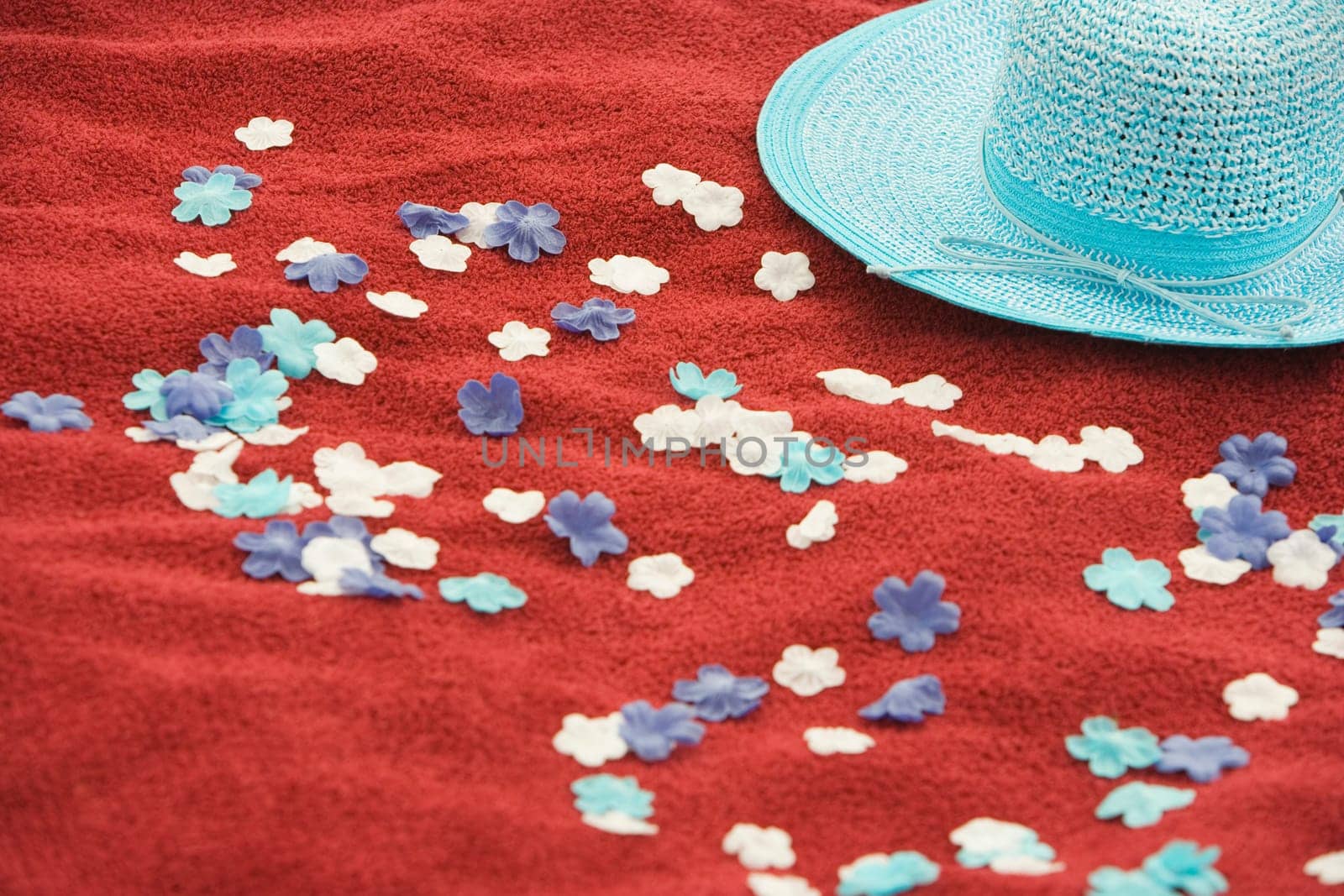 Close-up of artificial flowers with a hat on a picnic blanket