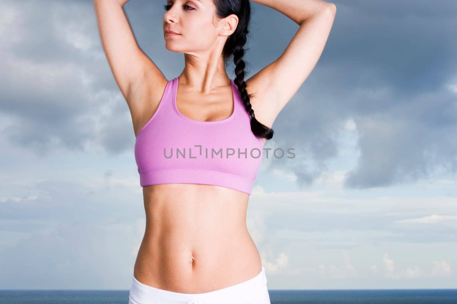 Close-up of a young woman standing with her arms raised