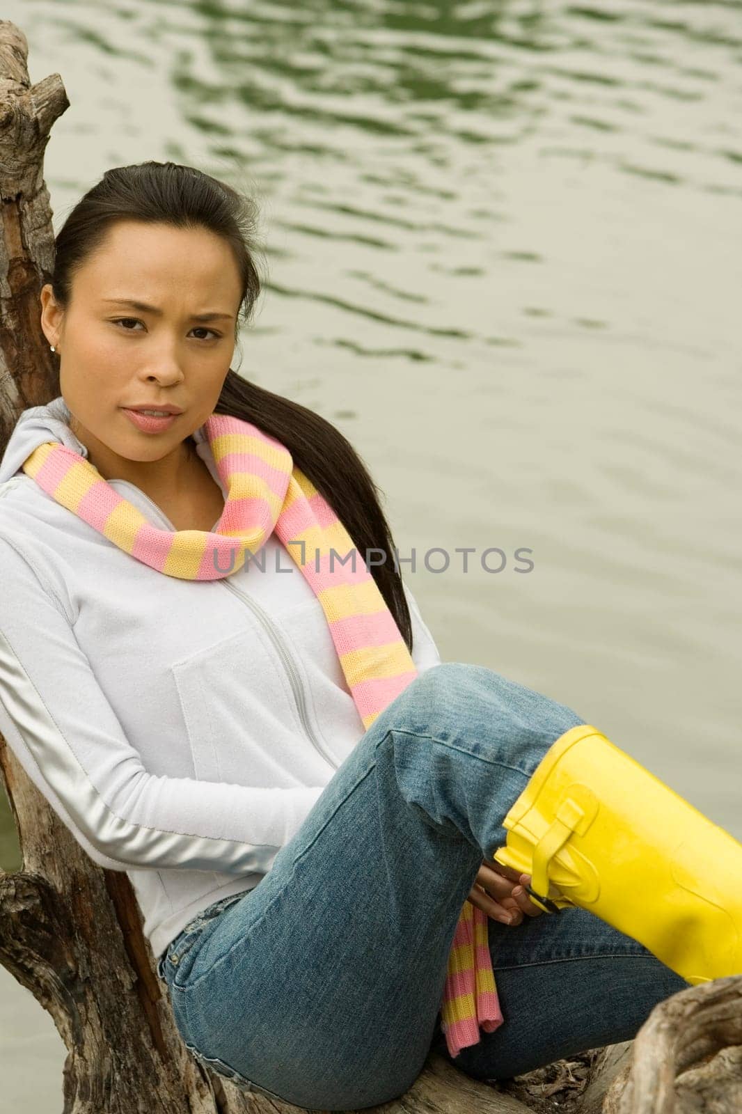 Portrait of a young woman sitting on a tree trunk by the lake