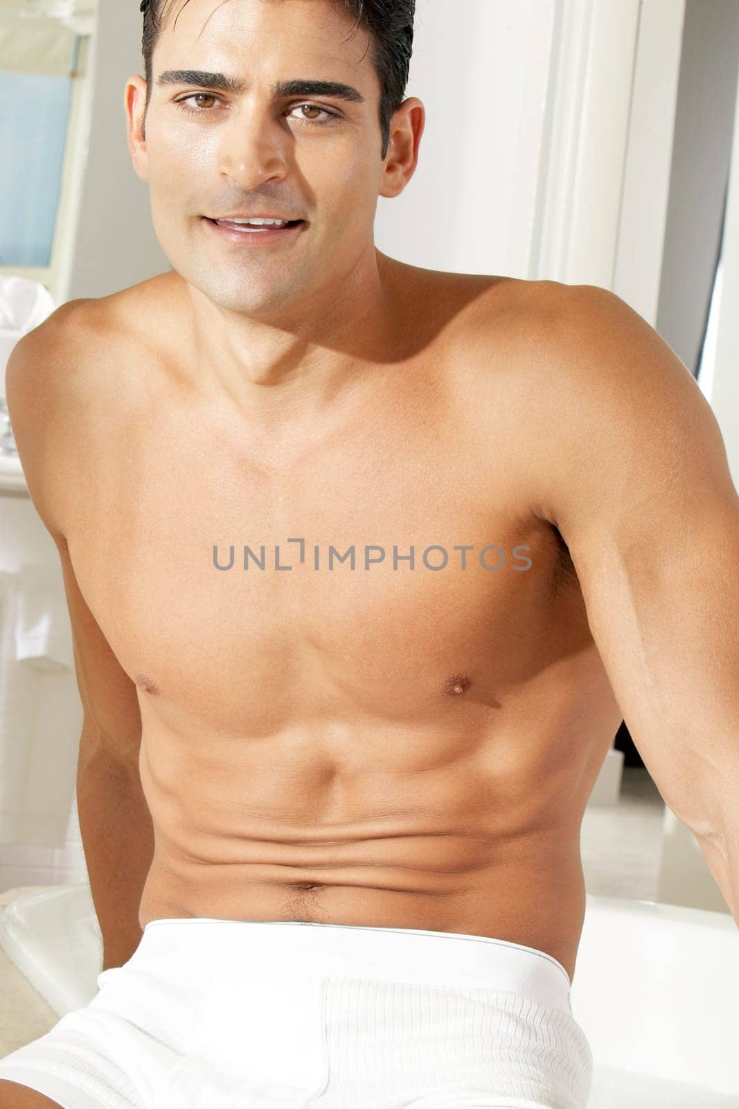 Portrait of a young man sitting at the edge of a bathtub