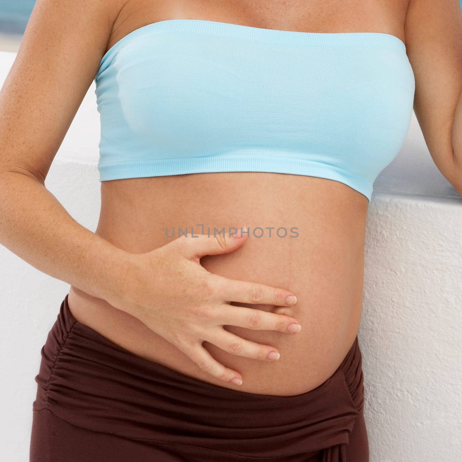 Mid section view of a pregnant woman touching her abdomen