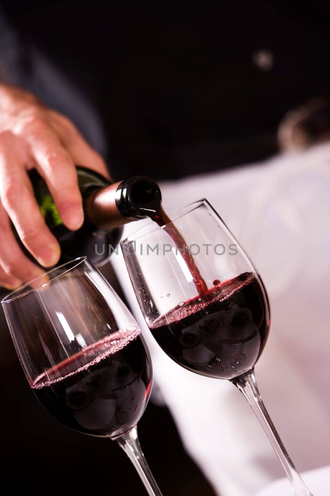 Mid section view of a man pouring red wine into a wineglass
