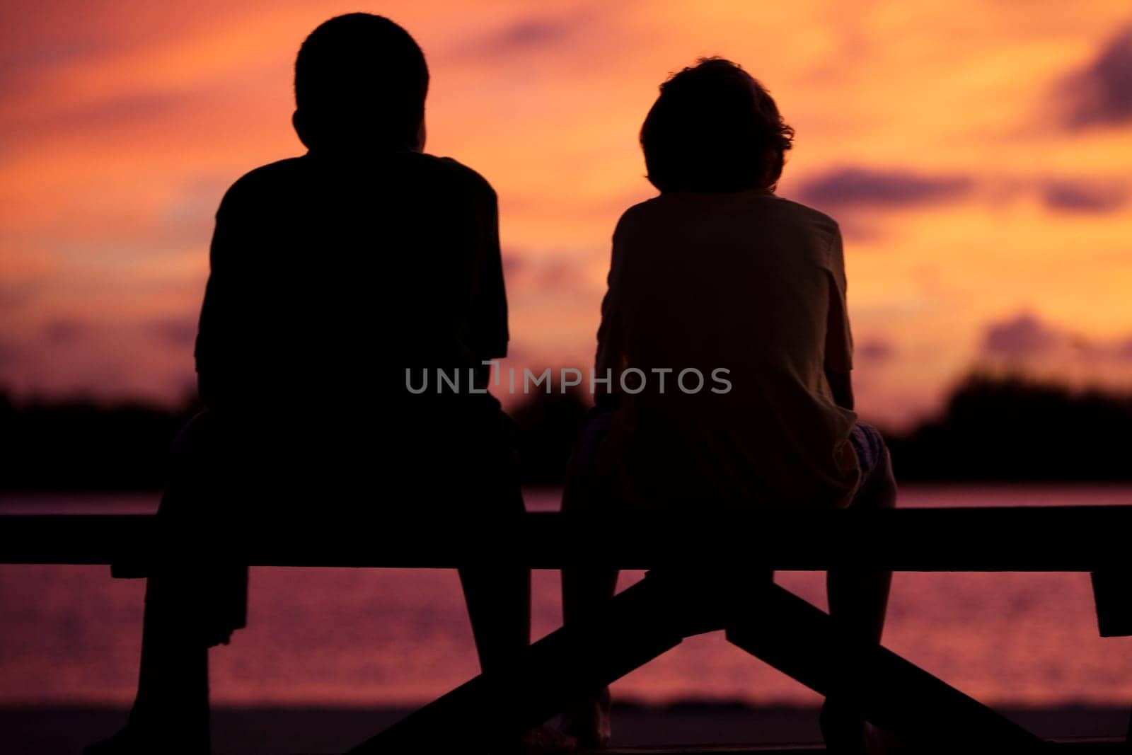 Silhouette of two boys sitting on a picnic table