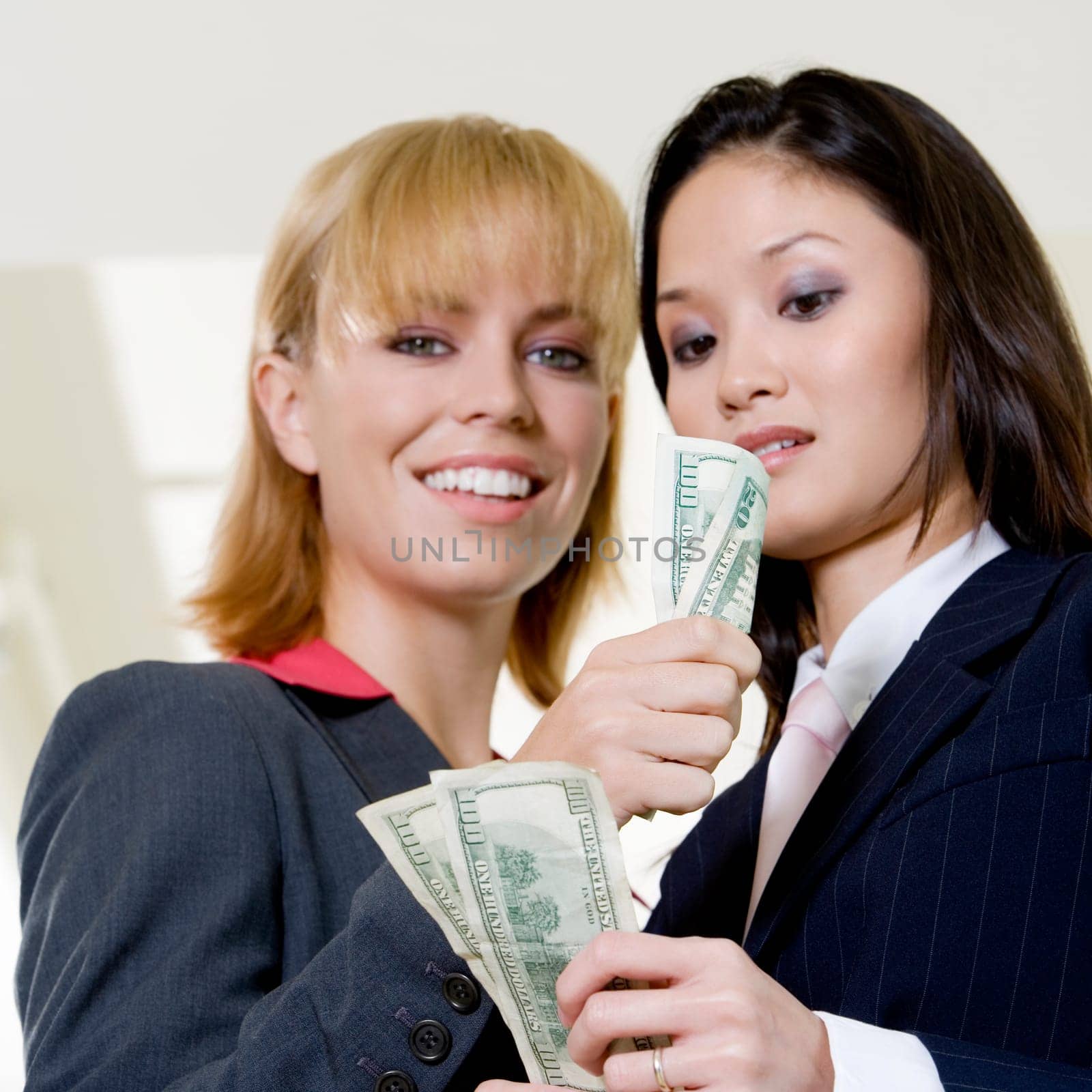 Low angle view of a businesswoman showing a dollar bill to another businesswoman