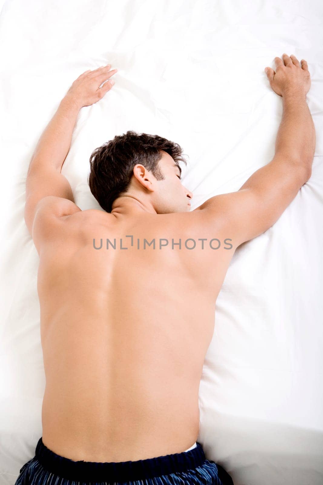 Rear view of a mid adult man sleeping on a bed