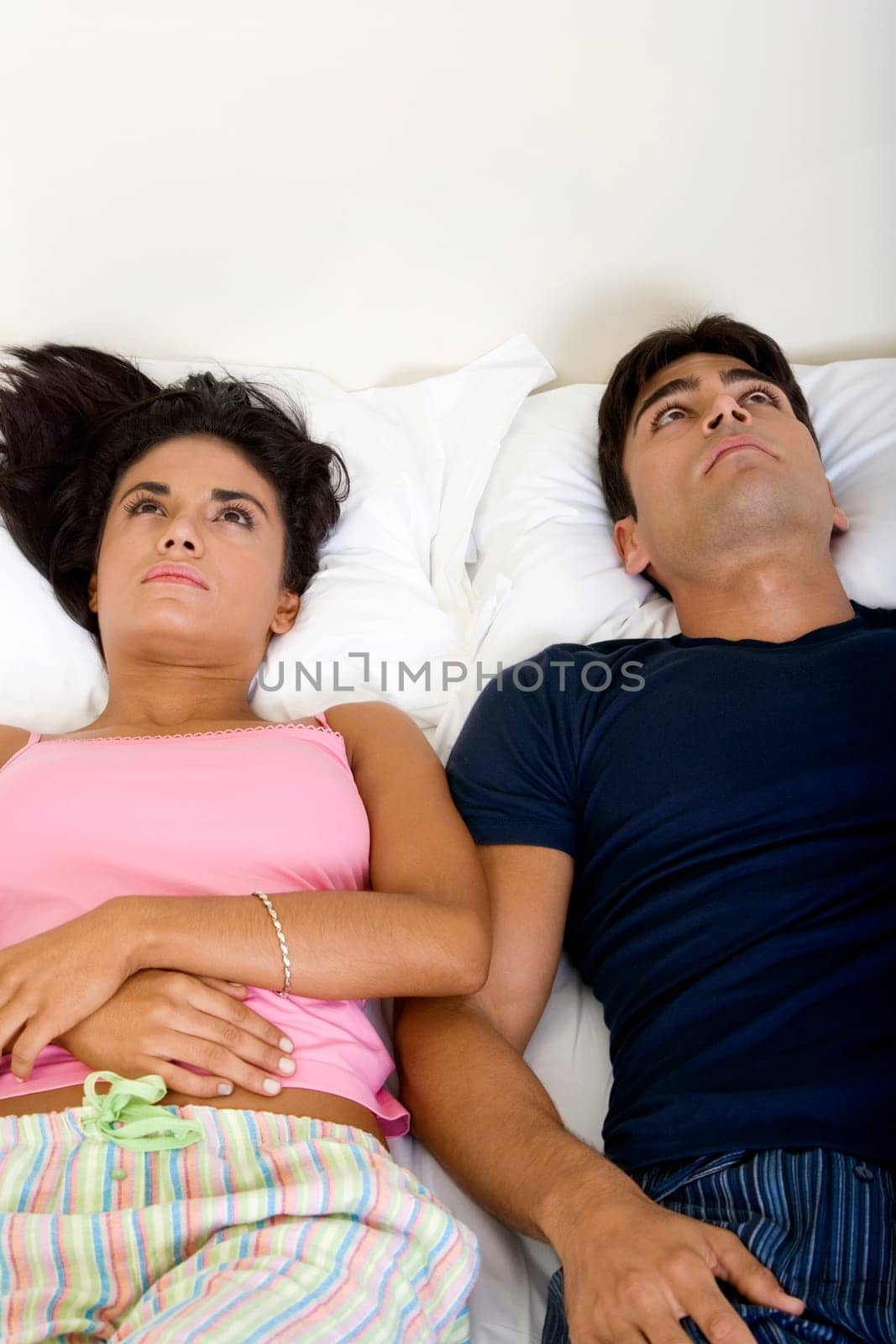 High angle view of a young couple lying on the bed looking up