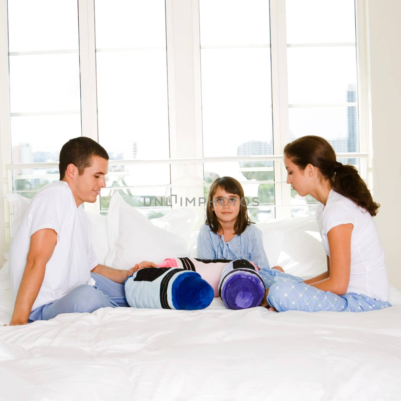 Parents and their daughter sitting on the bed