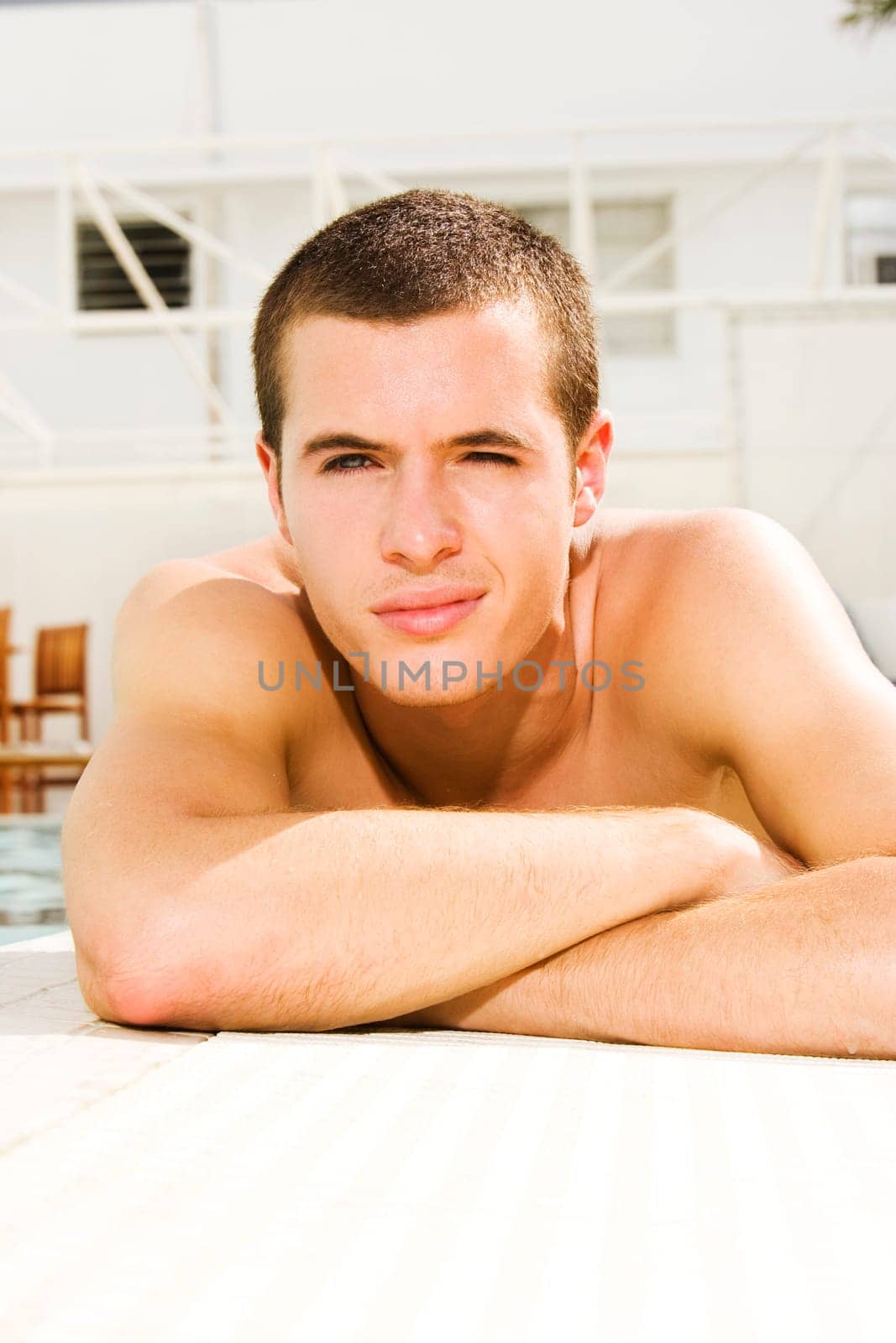 Portrait of a young man lying at the poolside