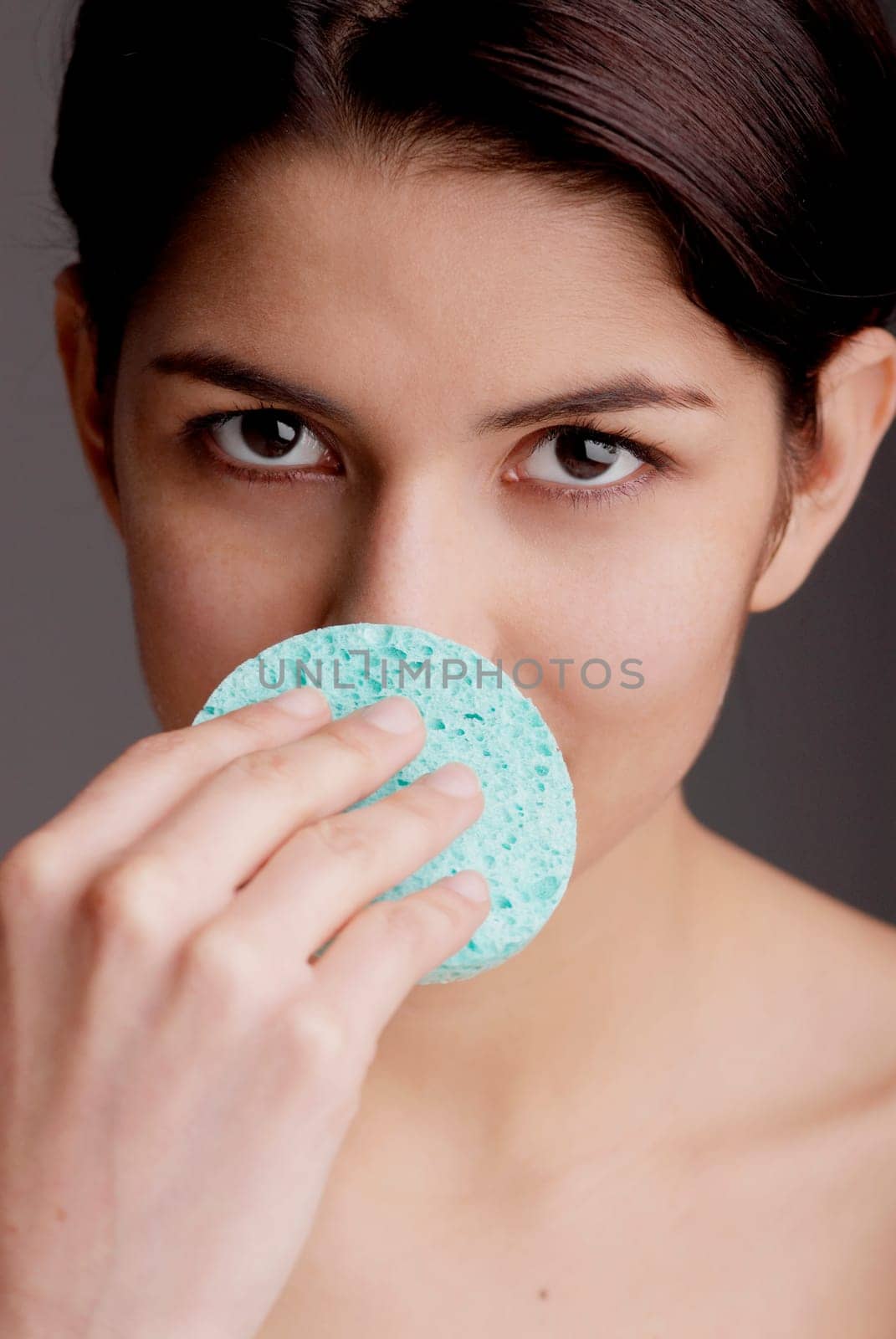 Portrait of a young woman scrubbing her nose with a sponge