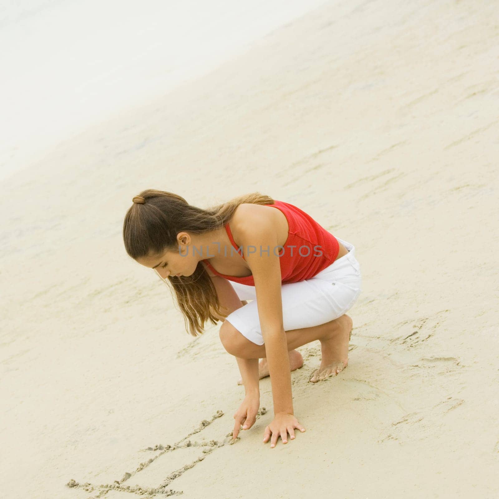 High angle view of a girl writing in sand