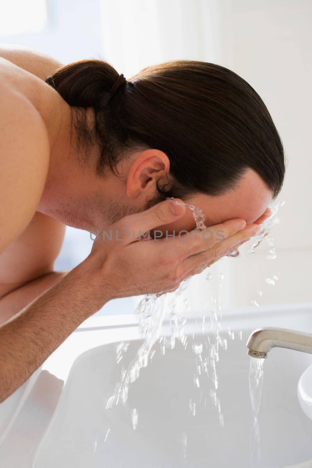 Close_up of a young man washing his face