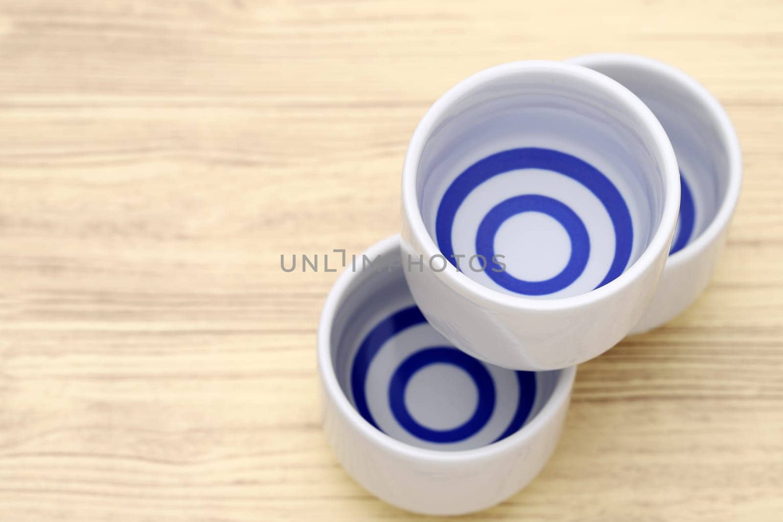 Japanese sake in traditional ceramic ochoko cup on wooden table