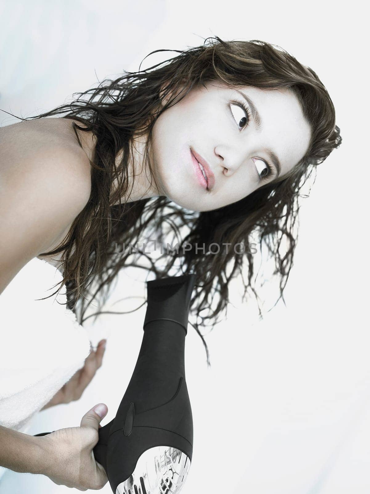 Side profile of a young woman drying her hair with a hair dryer