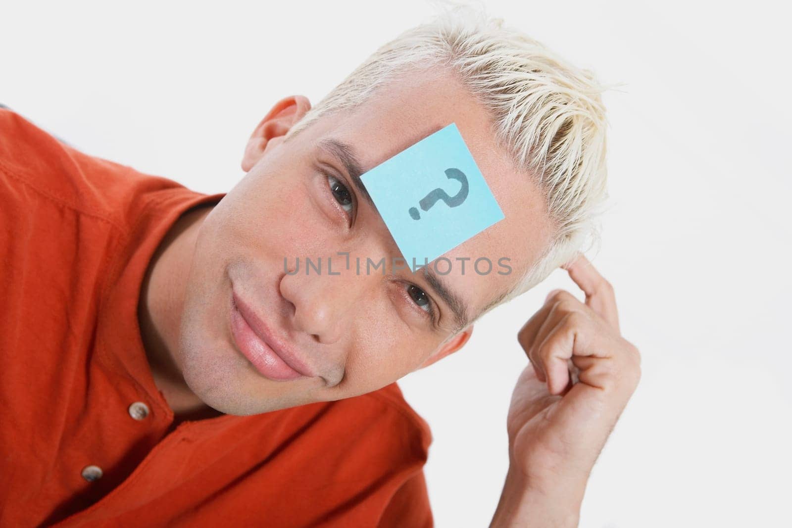 Portrait of a young man smirking with an adhesive note on his forehead