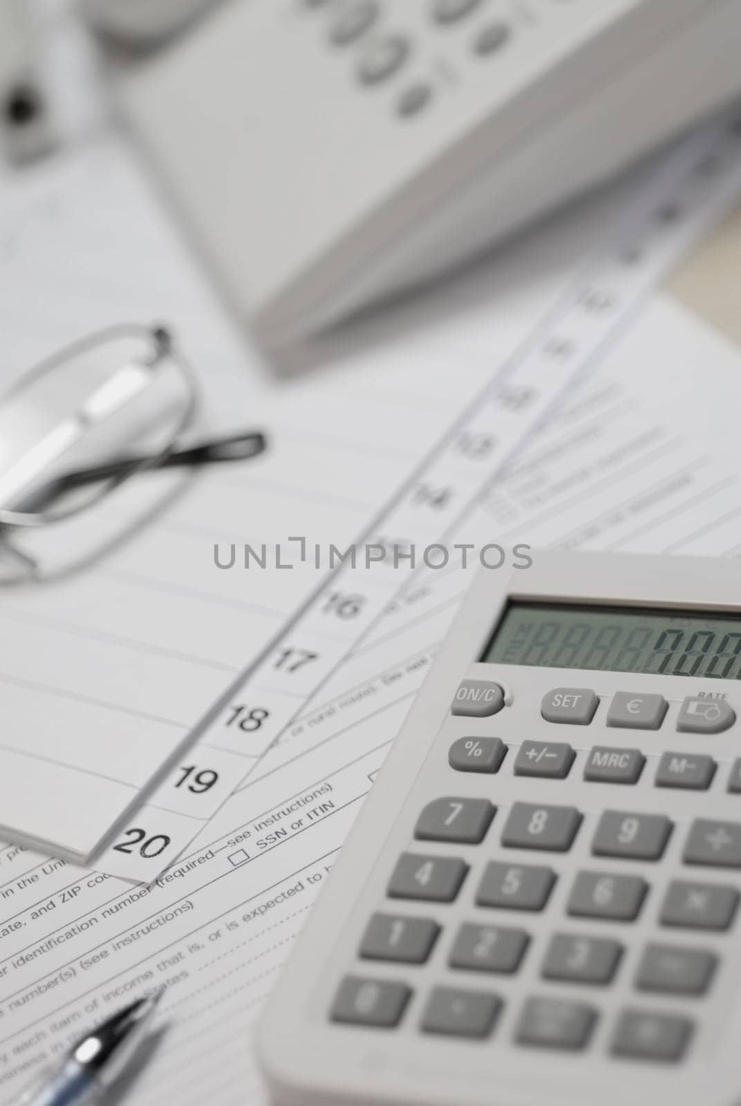 Calculator and telephone with eyeglasses on paper