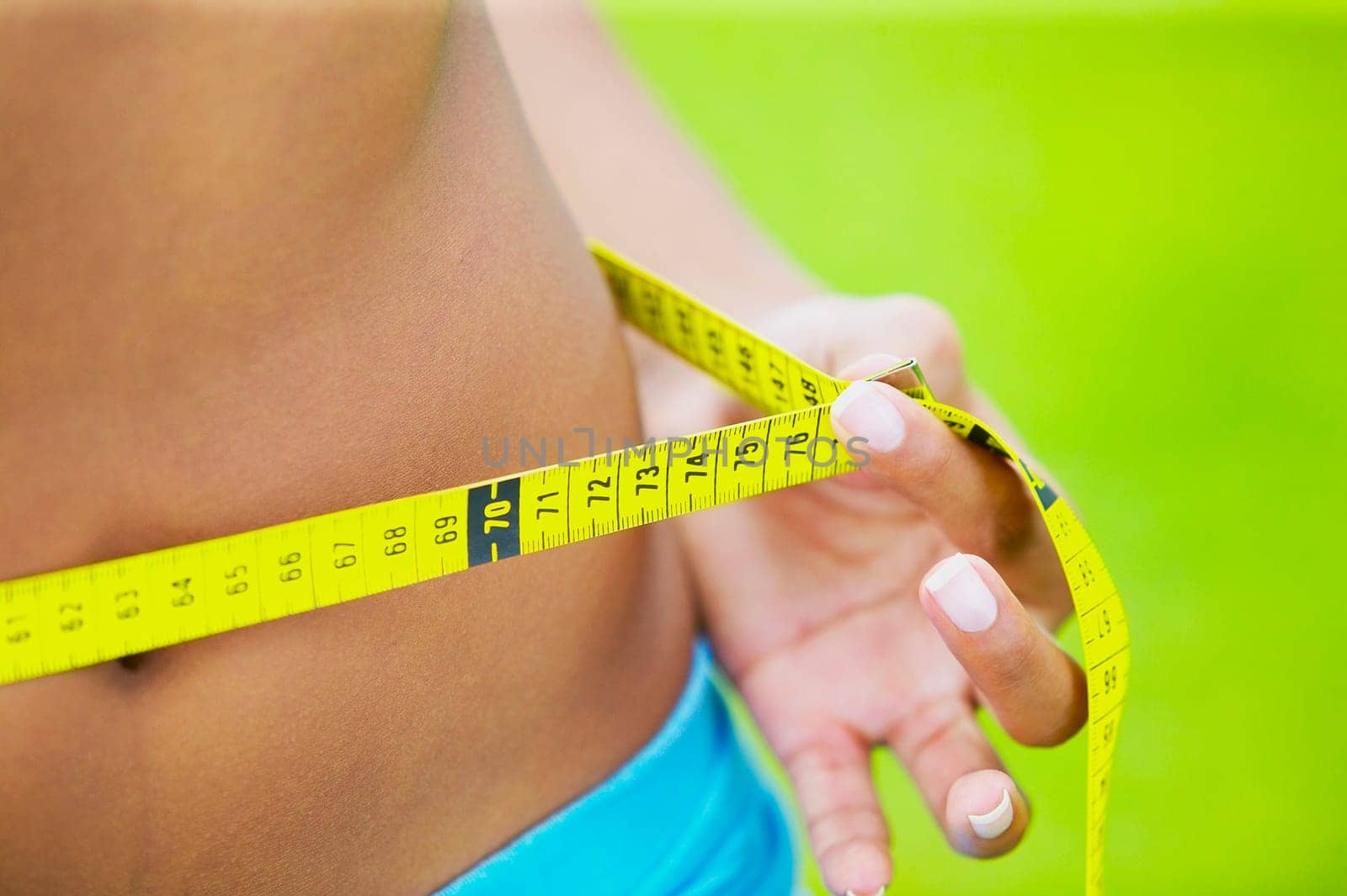 Mid section view of a woman measuring her waist with a tape measure