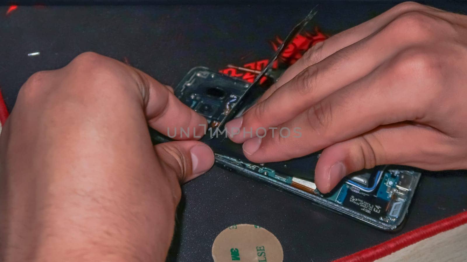 Close up of hands repairing smartphone with tools on a desk
