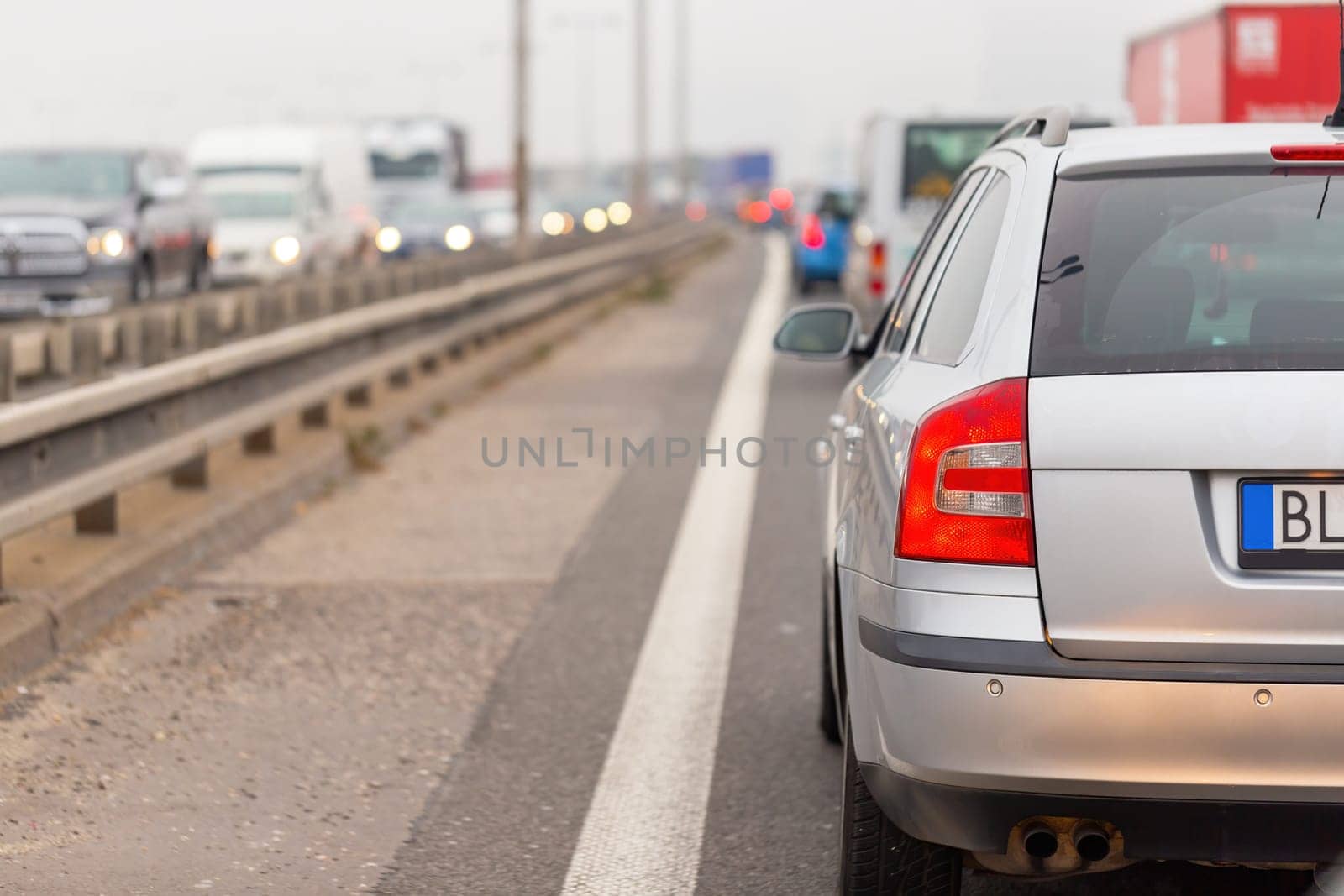 Car stucked in traffic jam on full road from back. Automobiles waiting on crowded highway with vehicles in opposite side. Collaps on motorway during rush hour.