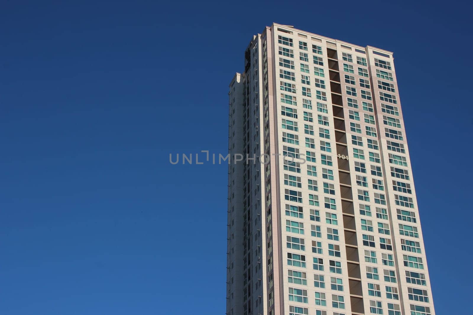 The wide-angle view of a skyscraper commercial building with blue sky on sunny day.