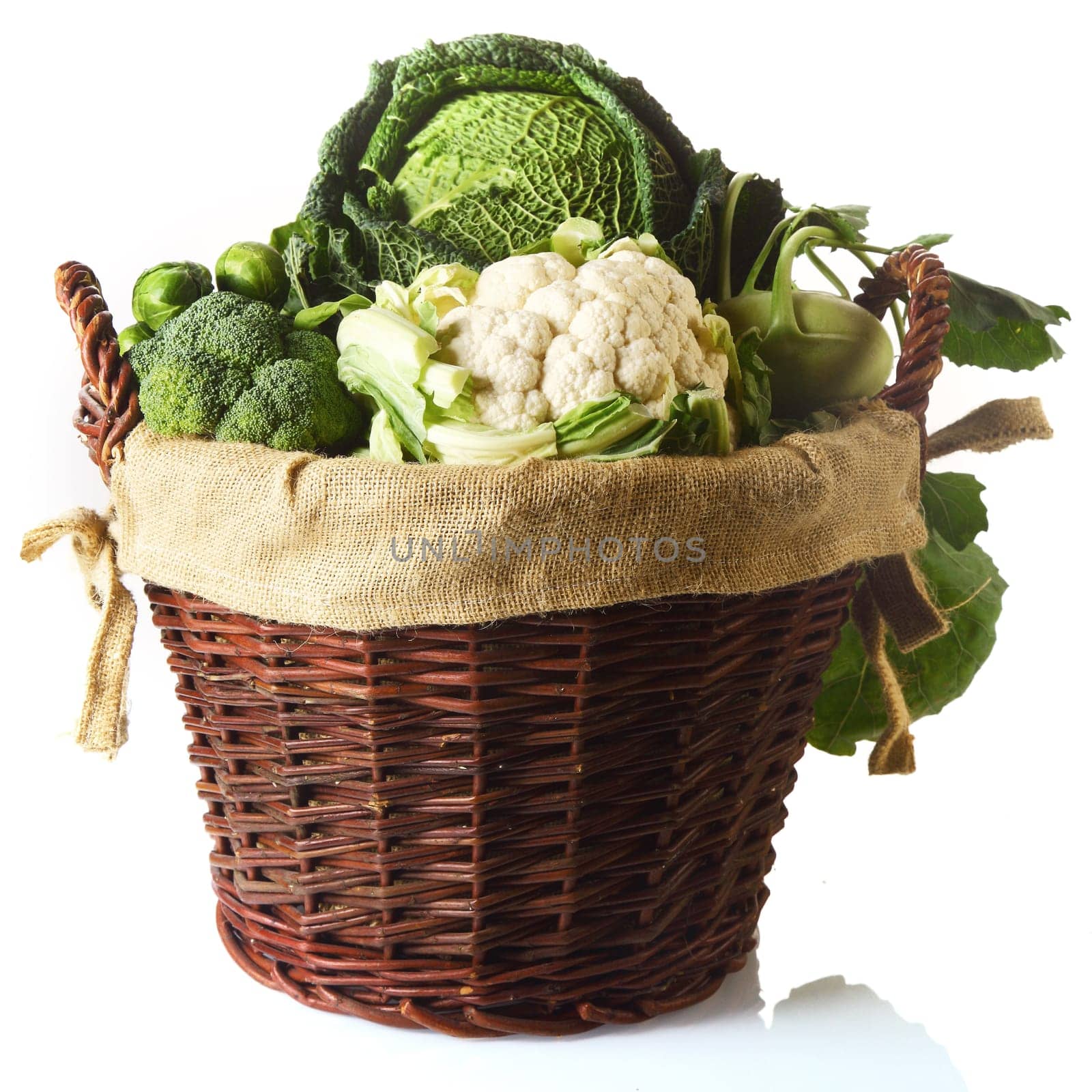 Close up Fresh Farm Vegetables in a Basket, Emphasizing Cauliflower, Brussels Sprouts, Broccoli and Cabbage. Isolated on White Background.
