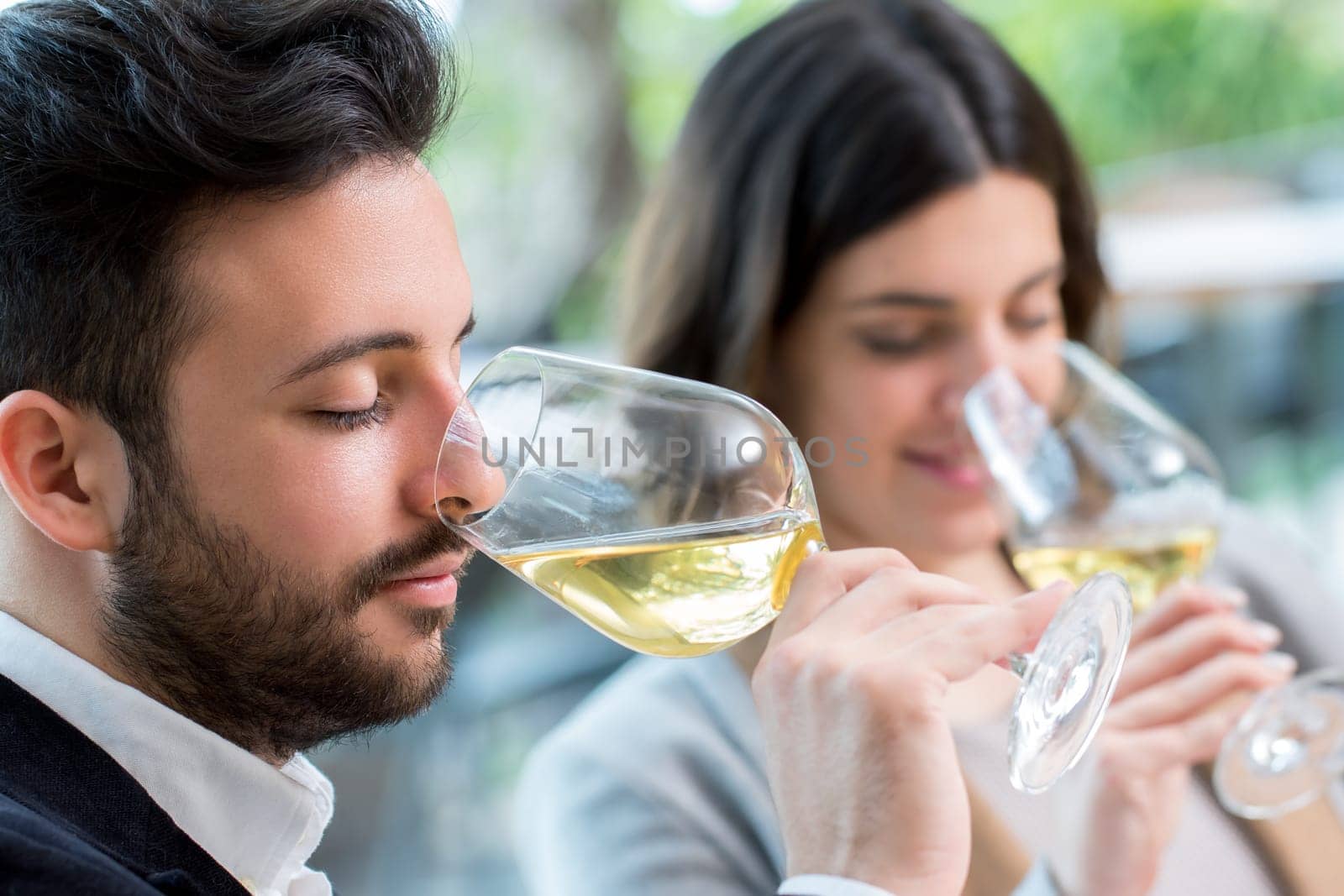 Close up portrait of young couple tasting white wine tasting.