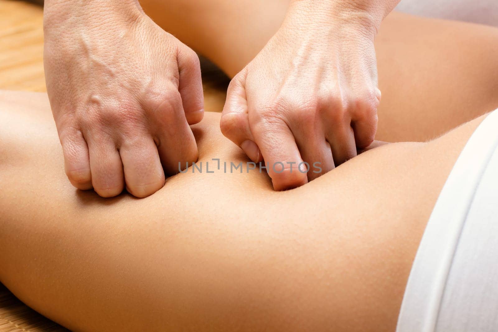 Close up Detail of hands massaging female hamstring.