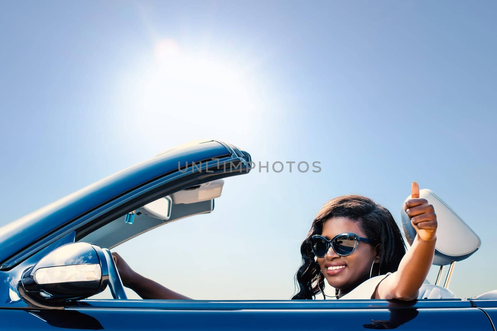 Close up portrait of young afro american girl sitting in convertible doing thumbs up.