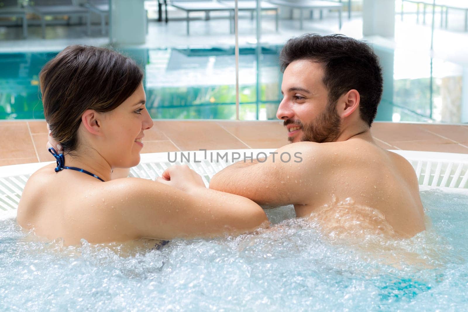 Close up portrait of attractive couple relaxing together in spa jacuzzi.