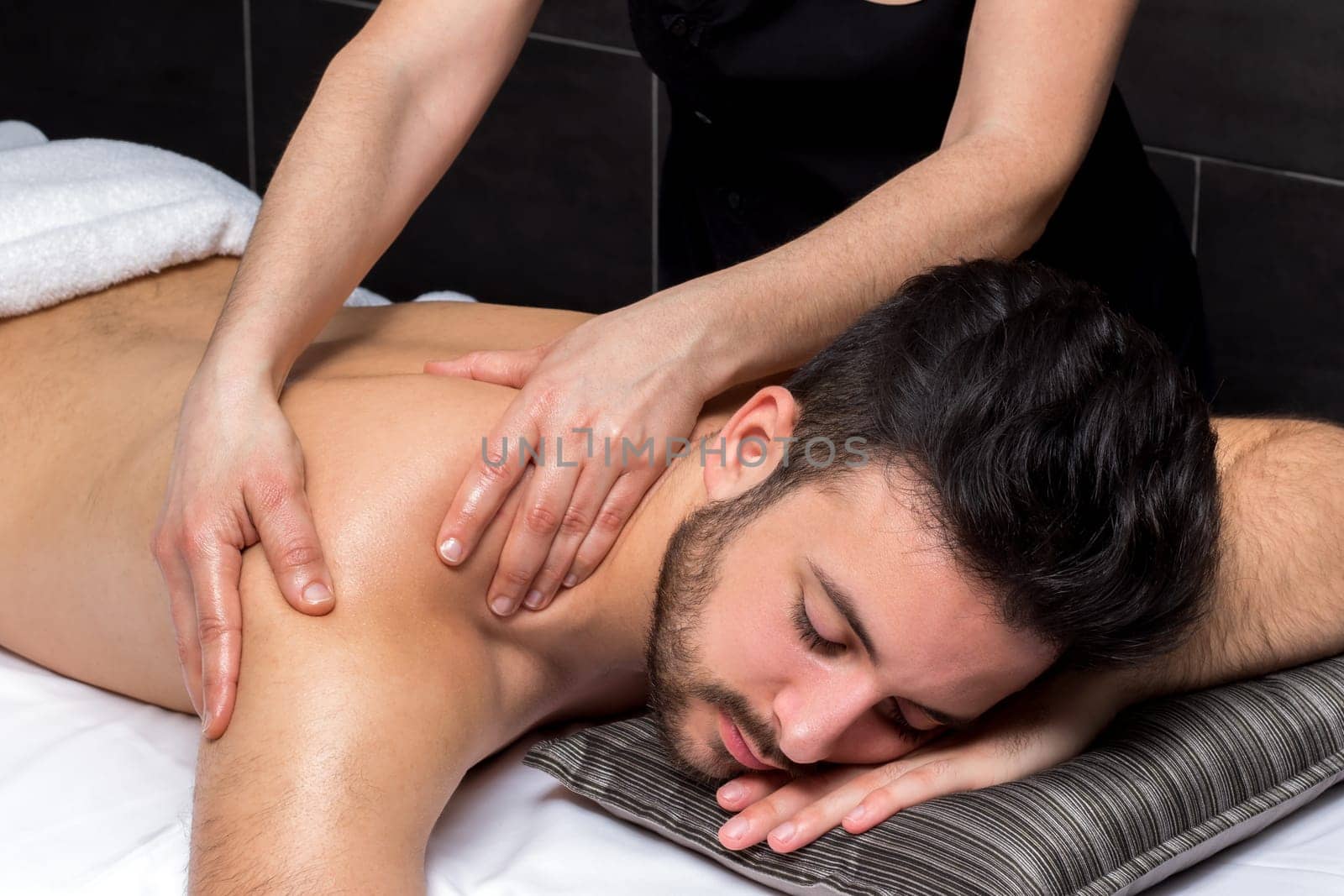 Close up of osteopath massaging young man’s back.