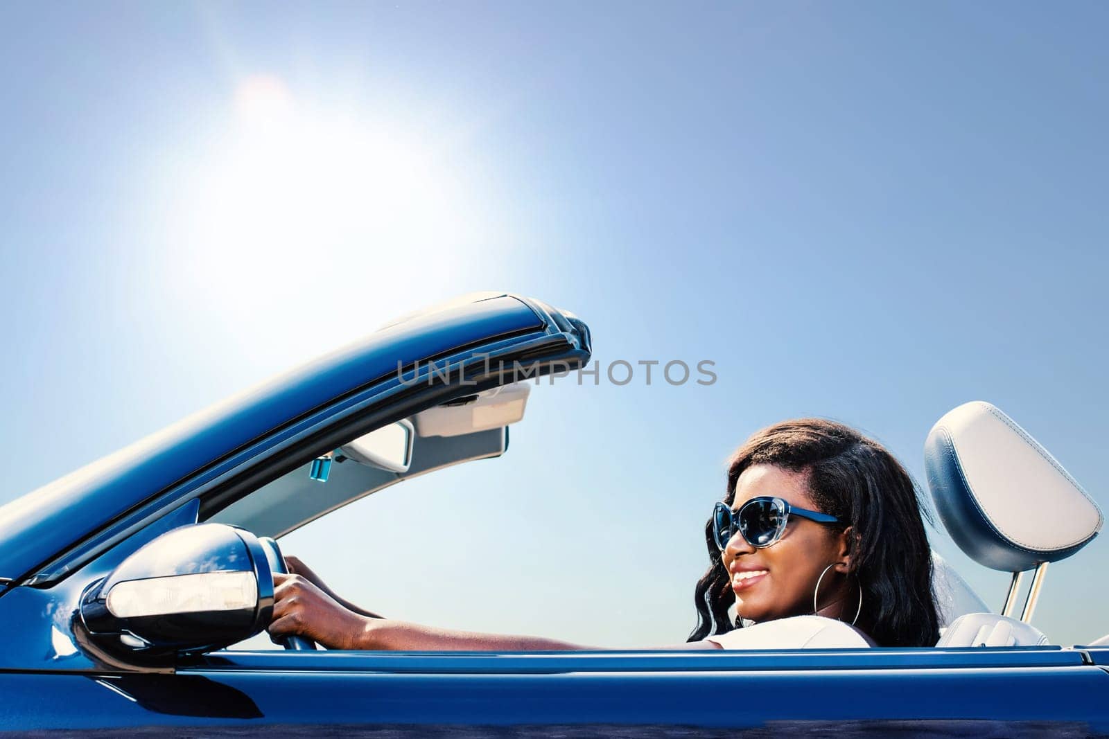 Close up portrait of young african girl taking blue convertible for a test drive.